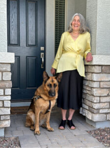 Libbi standing in front of a residential door with her dog.